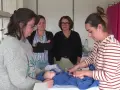 Des infirmières pédiatriques en formation observent et pratiquent les soins sur un poupon.