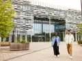 Deux étudiants marchent devant l'université métropolitaine de Manchester, un bâtiment moderne avec une façade à motifs.