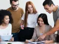 Une équipe diversifiée collabore sur un projet, comme un master moyen orient. Ils étudient des documents et utilisent une tablette.
