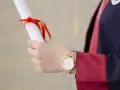 Main tenant un diplôme, une personne porte une robe de doctorat en anglais.