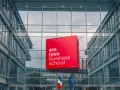 Le logo rouge d'EM Lyon Business School flotte devant un bâtiment moderne en verre. Idéal pour un master project management.