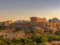 L'Acropole d'Athènes baignée de soleil, un site historique qui rappelle le coût de la vie en Grèce, entre ruines antiques et verdure luxuriante.