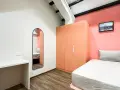 Chambre moderne pour **logement étudiant à Singapour** : lit, bureau, armoire corail et miroir mural.