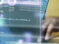 Un expert en master cybersécurité à distance analyse des données complexes sur un écran, jonglant avec des codes et des graphiques.