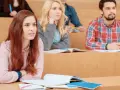 Étudiants en amphithéâtre, certains suivent un cours, d'autres pensent à leur doctorat en ligne.