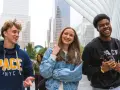 Trois étudiants souriants marchent dans le quartier financier de New York, un lieu idéal pour un MBA.