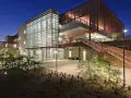 Bâtiment moderne d'un college aux États-Unis, avec une façade vitrée et des escaliers extérieurs en bois, éclairé la nuit.