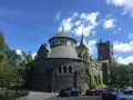 Bâtiment historique en pierre, rappelant une école de cinéma à Toronto, sous un ciel bleu et nuageux.