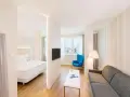 Chambre moderne avec lit, canapé, TV et vue sur la ville. Idéal pour un logement étudiant à Vienne, Autriche.