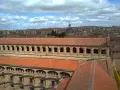 Vue aérienne de l'université pontificale de Salamanque, avec ses toits de tuiles rouges et son dôme emblématique sous un ciel nuageux.