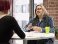 Une aide soignante belge, souriante, discute avec une patiente.