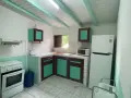 Cuisine fonctionnelle pour un logement étudiant en Guadeloupe : cuisinière, réfrigérateur, micro-ondes, évier et rangements.