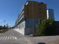 Immeuble moderne avec balcons vitrés, idéal pour le logement étudiant à Stockholm. Une piste cyclable longe le bâtiment.