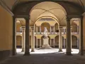 Cour intérieure de l'université de Pavie, avec une statue au centre, entourée d'arcades et de colonnes.