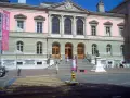 Bâtiment de l'université de Genève, avec une bannière "Université de Genève" et un buste sur un piédestal.