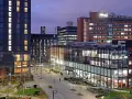 Bâtiments modernes illuminés le soir, avec une enseigne Alliance Manchester Business School visible.