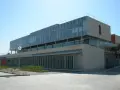 Bâtiment moderne aux lignes épurées, possiblement une école d'élite à Madrid, avec de grandes baies vitrées et une façade en pierre claire.