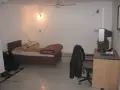 Chambre modeste en Inde, avec un lit, un bureau et une télévision. Un aperçu du cout de la vie en Inde.
