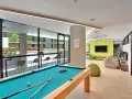 Salle commune moderne pour logement étudiant à Sydney, avec table de billard, poufs et espace extérieur visible.
