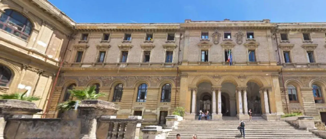 Grand bâtiment à Rome, avec une entrée imposante et des drapeaux italiens. Un lieu pour master Rome.