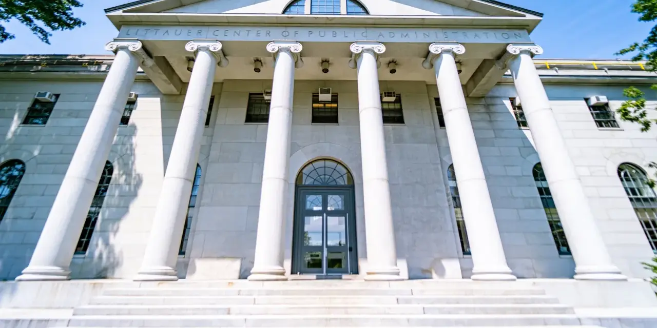 Le Littauer Center of Public Administration, un bâtiment emblématique d'une université américaine connue, se dresse fièrement avec ses colonnes imposantes et son escalier majestueux.