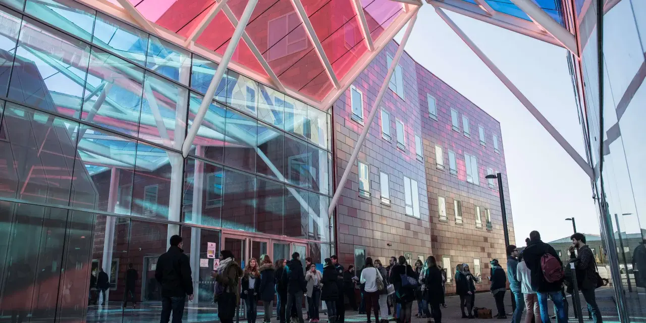Étudiants devant le bâtiment moderne de l'ICN Business School, avec sa façade vitrée et son toit coloré.