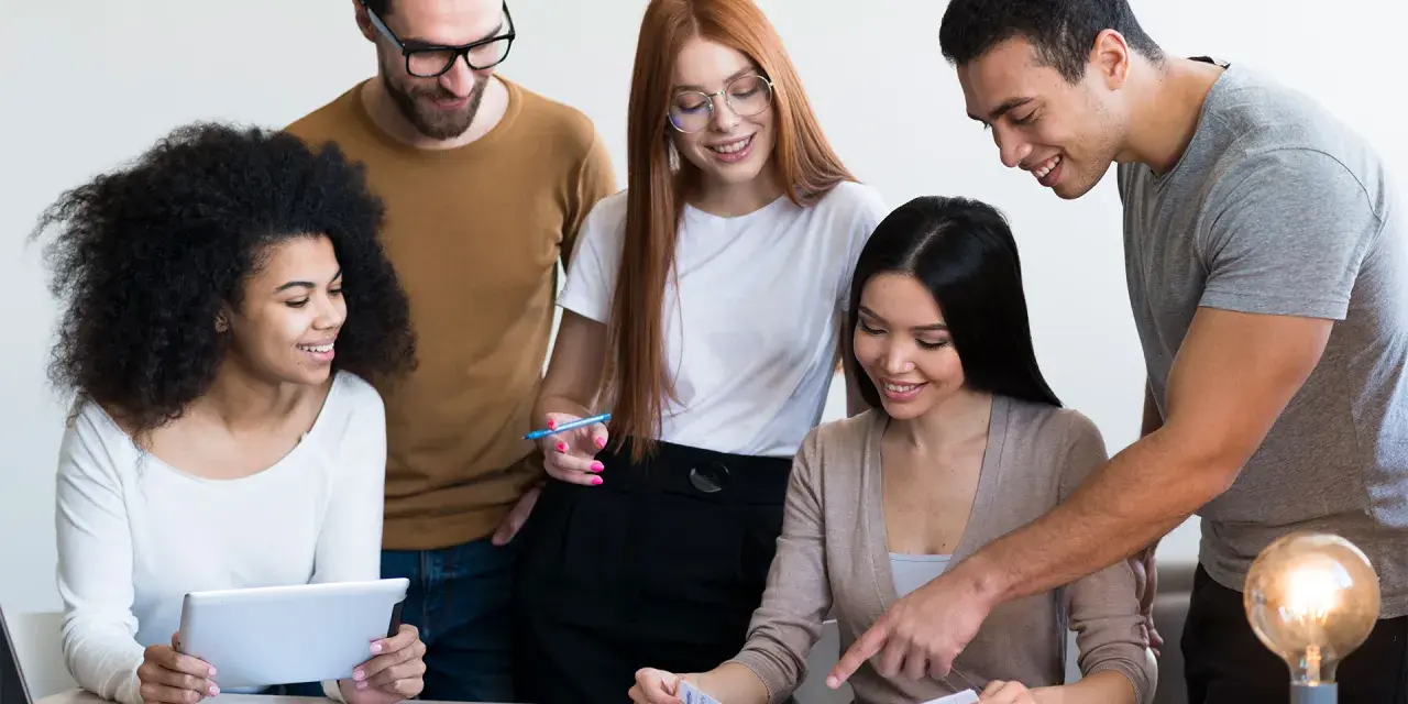 Une équipe diversifiée collabore sur un projet, comme un master moyen orient. Ils étudient des documents et utilisent une tablette.