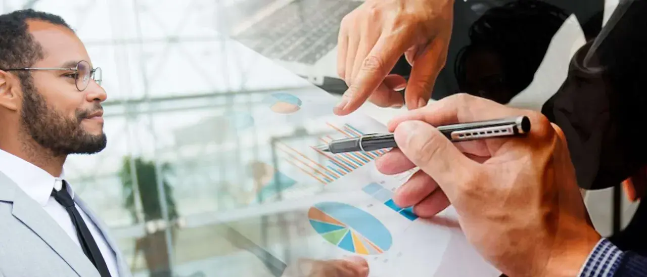 Un homme en costume regarde des graphiques financiers. Des mains analysent des données, suggérant une licence finance à distance.