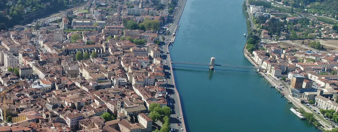 Vue aérienne de la ville de Vienne, traversée par un fleuve et un pont. L'école de Vienne se reflète dans l'eau.