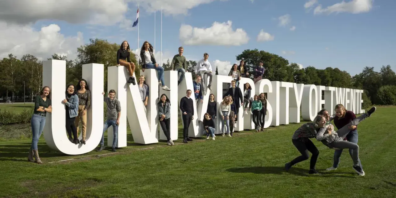 Un groupe d'étudiants pose joyeusement devant les lettres géantes "UNIVERSITY OF TWENTE".
