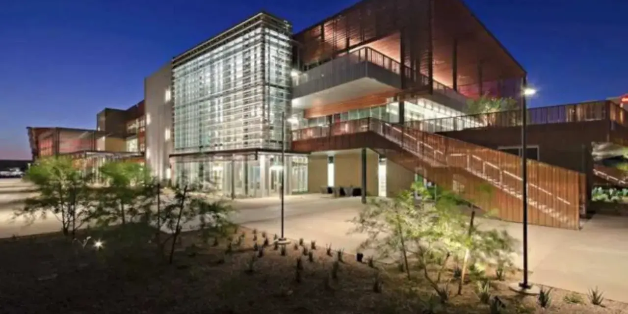 Bâtiment moderne d'un college aux États-Unis, avec une façade vitrée et des escaliers extérieurs en bois, éclairé la nuit.
