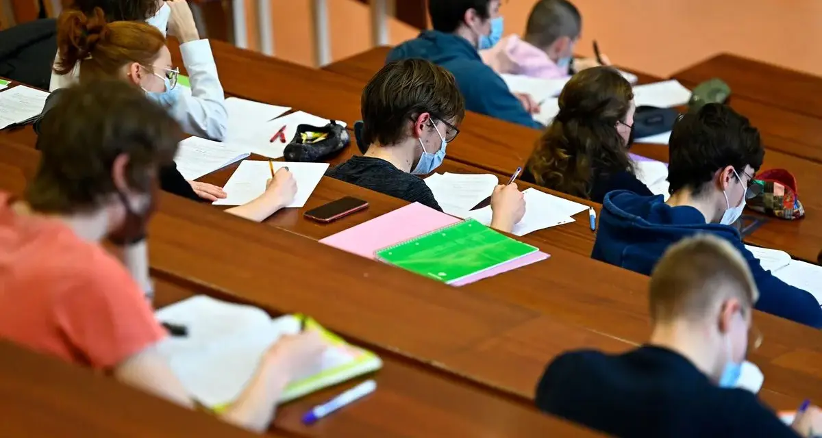 Étudiants masqués en classe, concentrés sur leurs notes. Un aperçu du coût de la vie au Danemark, où l'éducation est une priorité.