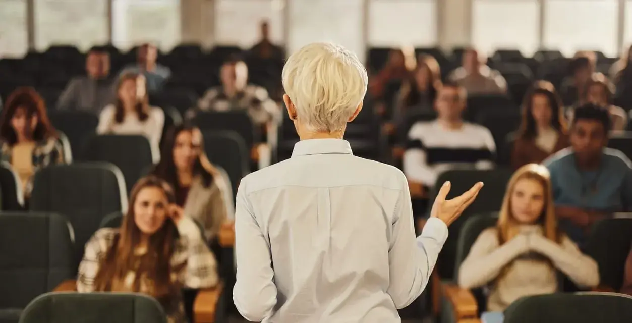 Professeure s'adressant à des étudiants dans un amphithéâtre, un lieu d'apprentissage pour une école de commerce publique gratuite.