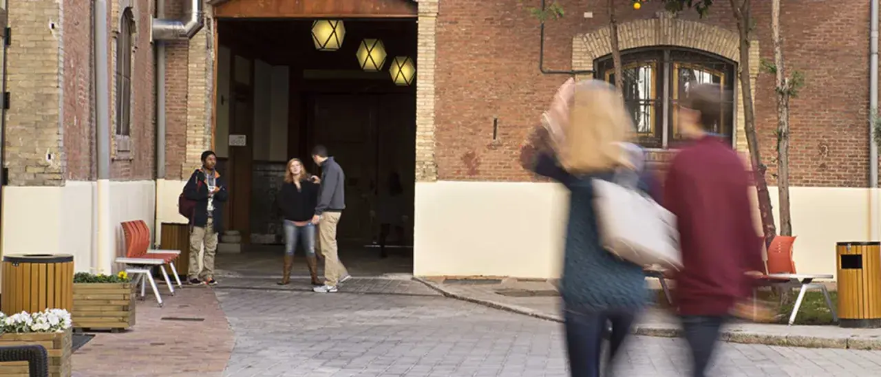 Des étudiants discutent dans une cour d'une vieille bâtisse, un lieu qui pourrait être un master à Madrid.