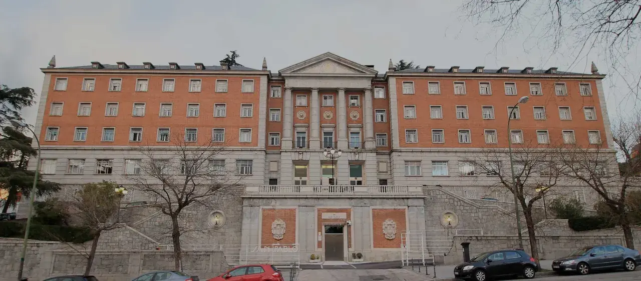 Bâtiment en brique avec des colonnes, des fenêtres et un toit mansardé. Le nom "CEU San Pablo" est visible sur la façade.
