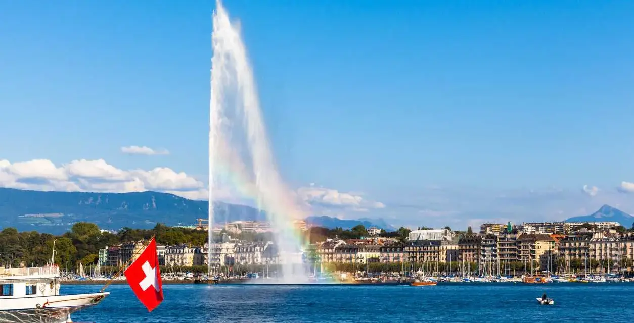 Le Jet d'Eau de Genève, un arc-en-ciel dans la brume, symbolise la beauté de comment vivre en Suisse.