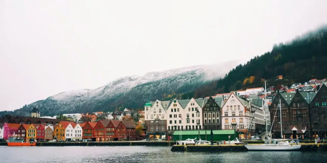 Vue du port de Bergen, Norvège, avec ses maisons colorées et ses montagnes enneigées. Un aperçu du coût de la vie en Norvège.