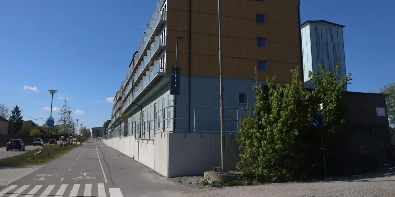 Immeuble moderne avec balcons vitrés, idéal pour le logement étudiant à Stockholm. Une piste cyclable longe le bâtiment.