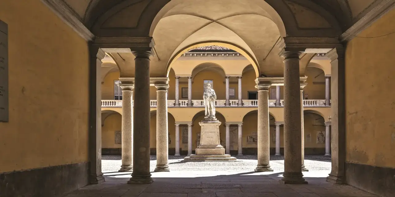 Cour intérieure de l'université de Pavie, avec une statue au centre, entourée d'arcades et de colonnes.