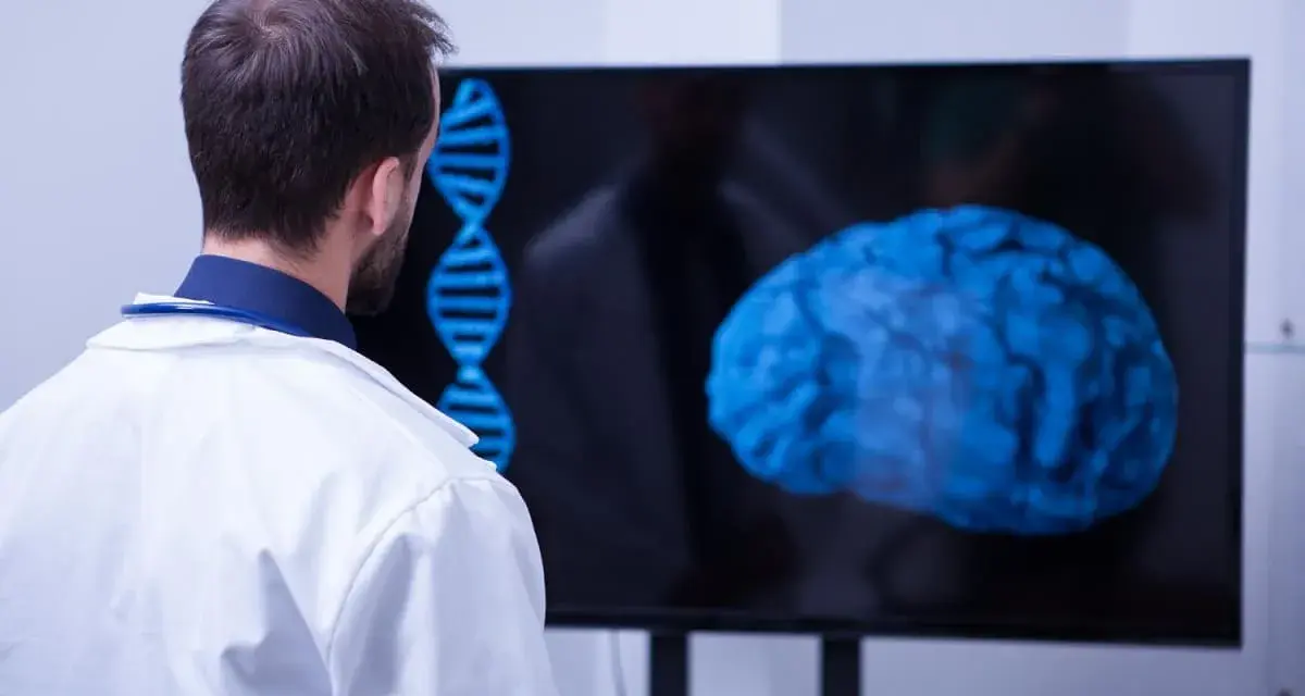 Un médecin observe un cerveau bleu et une double hélice sur un écran, signe d'une formation neuropsychologie à distance.