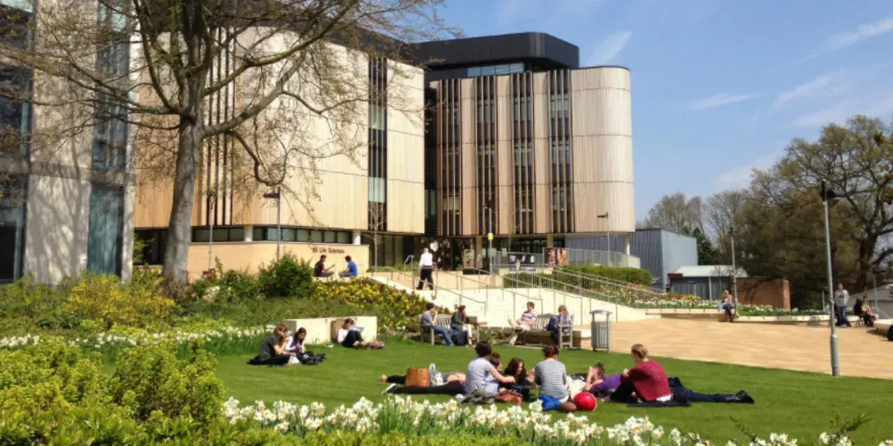 Étudiants profitant du soleil sur la pelouse devant le bâtiment de la **université de Southampton**.