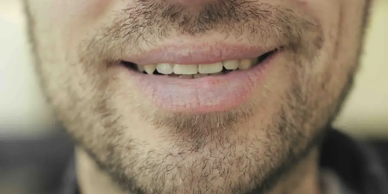 Un sourire d'homme barbu, peut-être réfléchissant au coût des études de dentiste pour un avenir radieux.
