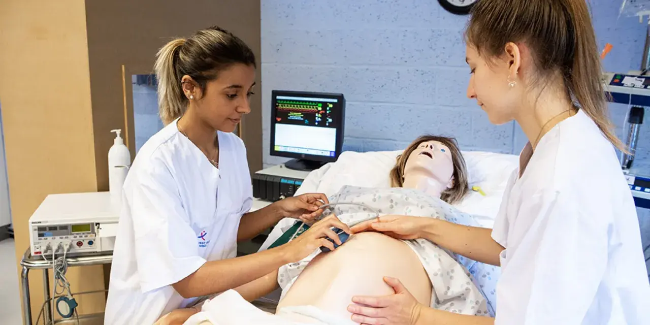 Étudiantes en sage-femme en Belgique pratiquant sur un mannequin de grossesse.