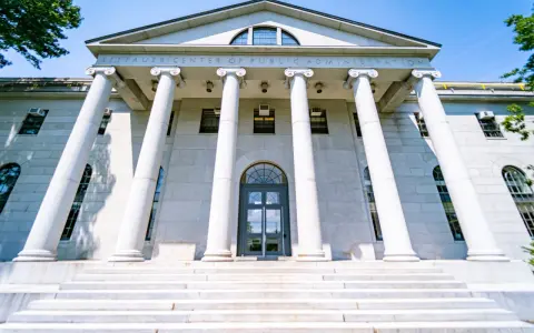 Le Littauer Center of Public Administration, un bâtiment emblématique d'une université américaine connue, se dresse fièrement avec ses colonnes imposantes et son escalier majestueux.