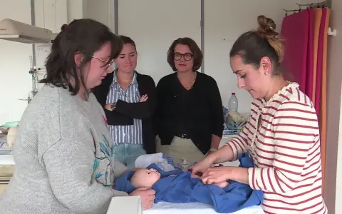 Des infirmières pédiatriques en formation observent et pratiquent les soins sur un poupon.