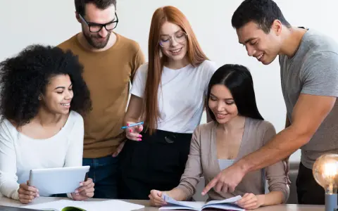 Une équipe diversifiée collabore sur un projet, comme un master moyen orient. Ils étudient des documents et utilisent une tablette.