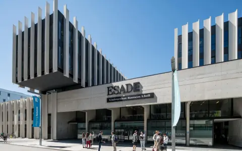 Devant l'ESADE Barcelone, une école reconnue pour son classement, des étudiants discutent sous un ciel bleu.