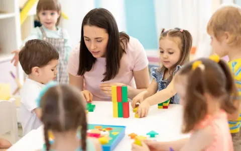 Une enseignante, experte en psychopédagogie à distance, guide des enfants jouant avec des blocs colorés.