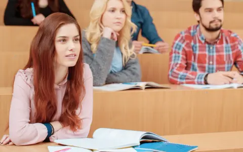 Étudiants en amphithéâtre, certains suivent un cours, d'autres pensent à leur doctorat en ligne.