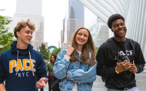 Trois étudiants souriants marchent dans le quartier financier de New York, un lieu idéal pour un MBA.
